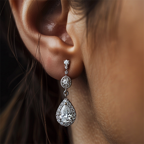 A beautiful pear diamond earring hanging from a woman's ear